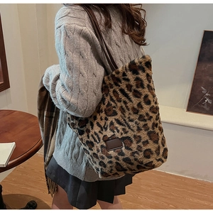Close-up of fluffy leopard print tote bag with brown leather handles and brand tag