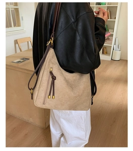Detail of matte suede hobo bag with vertical zipper and fringe tassels for daily commute