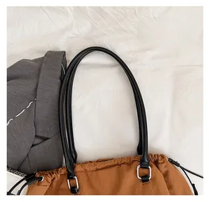 Detail of a brown casual tote bag featuring a black drawstring closure and leather handle