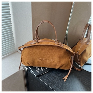 Detailed macro view of caramel suede handbag with embossed logo and metal zipper closure
