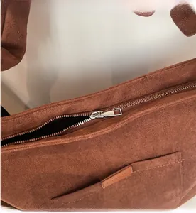 Detail of smooth metal zipper and brown suede texture on minimalist bucket bag