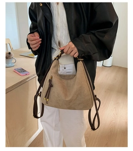 Detailed close-up of light brown suede hobo bag featuring stylish long leather side tassels