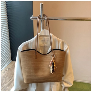 Détail du sac cabas en paille tissée avec pompon en perles et anses en cuir fin