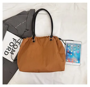Brown drawstring tote bag detail showing large capacity with an iPad for size comparison