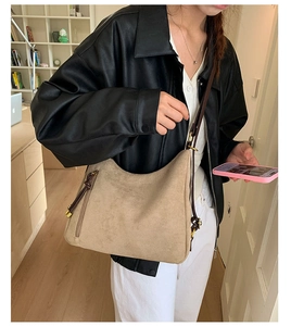 Detail of khaki suede hobo bag with tassel zippers and brown shoulder straps