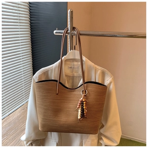 Détail du grand sac cabas tressé marron avec gland en perles de bois et fines lanières