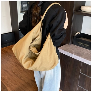 Détail du sac cabas en toile kaki avec bandoulière nouée et perles en bois sur l'épaule