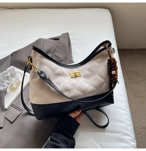 Detail of quilted beige suede shoulder bag with gold twist-lock and wooden bead charm
