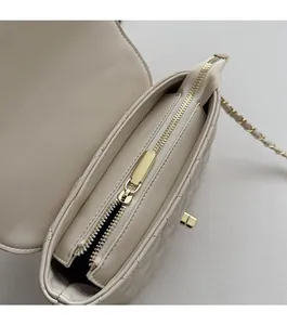 Close-up of quilted beige chain bag interior showing golden zipper and metal lock
