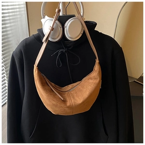 Detailed view of brown matte suede crescent bag with adjustable strap and top zipper