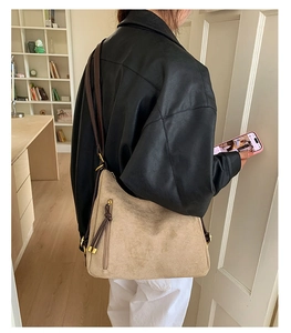 Detail view of beige matte suede shoulder bag with brown strap and vertical zipper