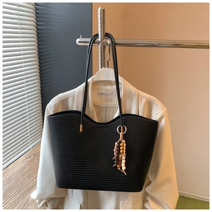 Détail d'un sac cabas en paille tissée noire avec pendentif en perles de bois rétro
