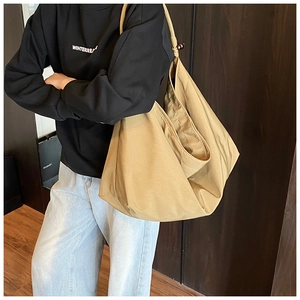 Vue latérale d'un grand sac cabas en toile kaki avec perle marron porté par un mannequin