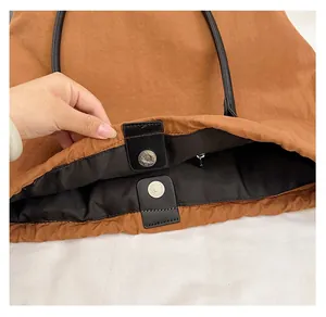 Close-up of brown fabric tote bag showing magnetic snap closure and black interior lining
