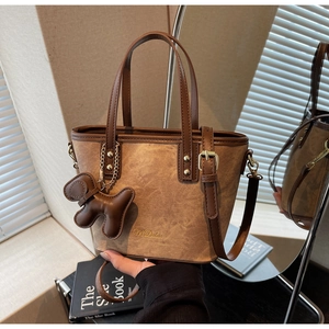 Detail of retro canvas tote bag with brown leather trim and golden hardware
