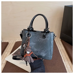 Dettaglio borsa a secchiello grigia strutturata con ciondolo a orsetto e logo fashion