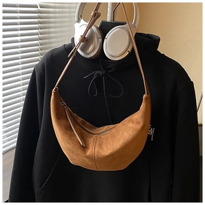 Detail of brown faux suede hobo bag featuring a metal zipper and long leather puller