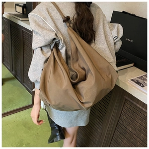 Détail du sac cabas minimaliste avec bandoulière nouée et accents de perles en bois