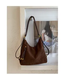 Detailed view of brown matte suede hobo bag featuring decorative metal zipper and fringe
