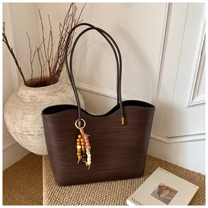 Détail d'un grand cabas tressé marron foncé avec pendentif bohème en perles de bois