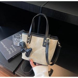Detail view of tote bag with black leather dog charm and adjustable shoulder strap