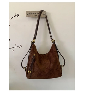 Detail of dark brown matte suede hobo bag with vintage brass hardware and fringe tassel