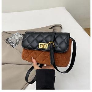 Detail of quilted two-tone crossbody bag with gold metallic twist lock on soft background