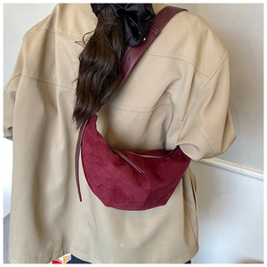 Detail of burgundy frosted suede crescent crossbody bag with fine stitching and strap