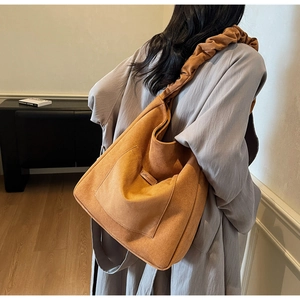 Detail of the oversized orange-brown corduroy tote with pleated cloud strap on model