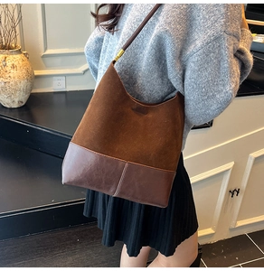 Detail of brown suede tote with leather stitching and golden metal buckle accents
