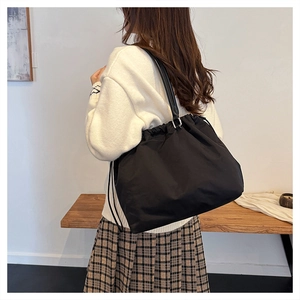 Detail of black drawstring tote bag in soft nylon material shown on shoulder