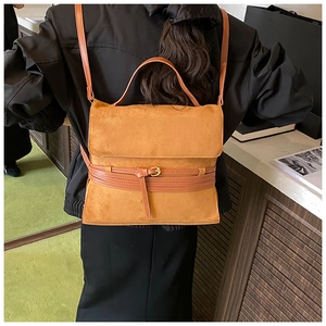Detalle de bolso de ante caramelo con correas cruzadas decorativas en modelo