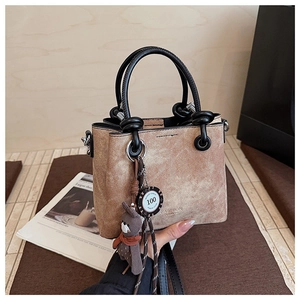 Dettaglio borsa a mano marrone vintage con ciondolo a orsetto e manico annodato