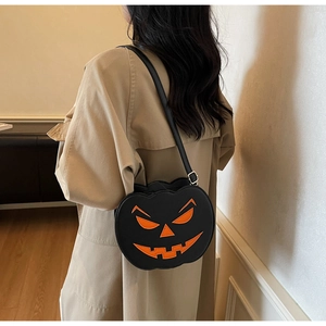 Detail of a black pumpkin-shaped shoulder bag with orange devil face print on a model