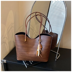 Gros plan du sac cabas tressé marron foncé orné d'un pendentif en perles colorées