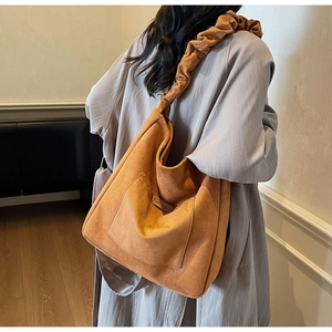 Close-up of brown suede tote bag with pleated cloud strap and decorative front pocket