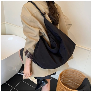 Détail d'un grand sac en toile noir en forme de croissant avec perle de réglage