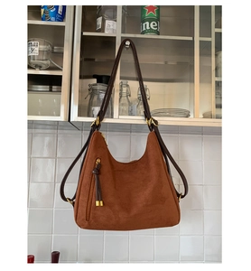 Detail of vintage matte brown hobo bag featuring a vertical zip pocket and tassel detail