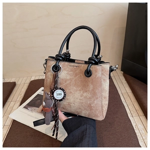 Dettaglio della borsa a secchiello marrone vintage con goffratura e ciondolo a orso