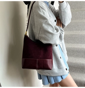 Détail du sac bandoulière bordeaux montrant la texture daim et la finition cuir lisse