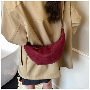 Close-up of burgundy suede hobo bag worn with a khaki coat showing rich fabric texture