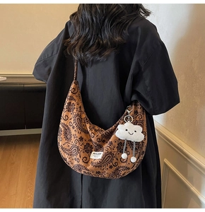 Nahaufnahme der braunen Paisley-Canvas-Tasche mit weißem Wolken-Plüschanhänger und Etikett