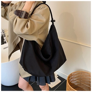 Détail du grand sac cabas noir avec bandoulière nouée et boucle réglable de style épuré