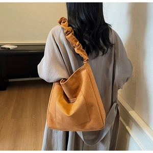 Detailed view of caramel suede tote bag with ruched cloud shoulder strap and front pocket