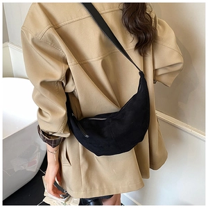 Detail view of the black crescent crossbody bag worn over a casual jacket for a modern look