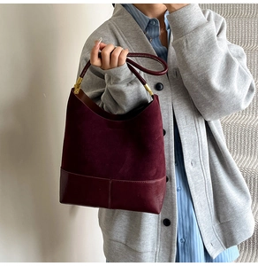 Détail du sac seau bordeaux en daim et cuir porté par un mannequin sur un gilet