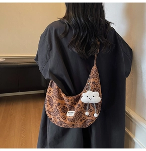 Detailansicht der Rückseite einer braunen Paisley-Halbmondtasche mit flauschigem Wolkenanhänger