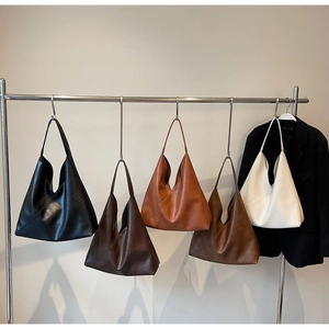 Detail view of five large minimalist tote bags in diverse colors hung on a metal rack