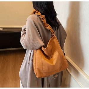 Detail view of large orange-brown suede tote bag with pleated cloud shoulder strap