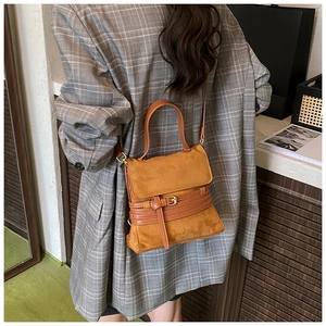 Bolso de ante marrón con correas decorativas lucido por modelo en estilo urbano informal